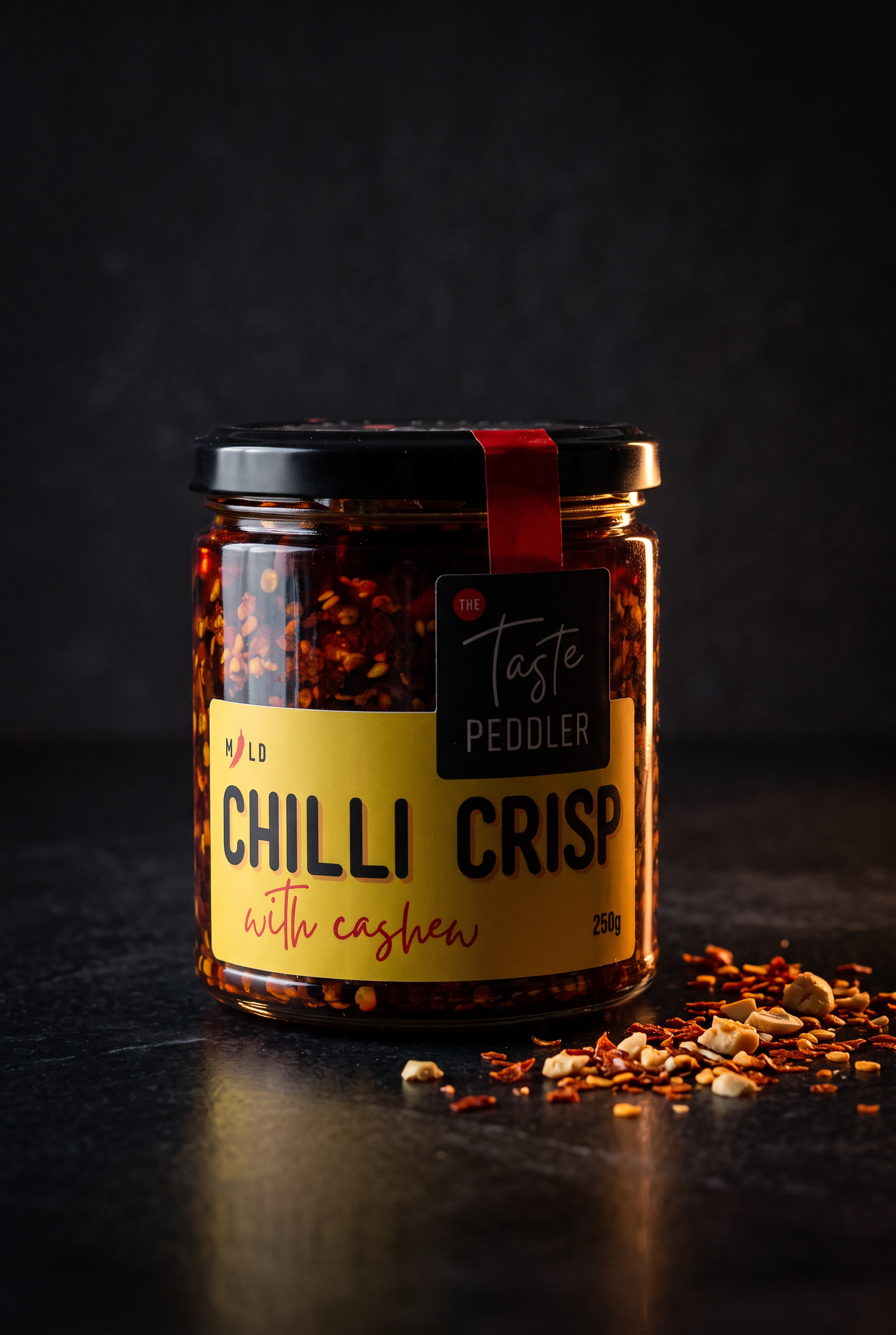 Jar of Taste Peddler chilli crisp with cashew lit against a dark backdrop